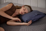 A woman sleeping comfortably on her side on a grey patterned cooling mattress with a blue hypoallergenic pillow.