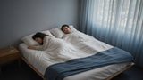 Woman rolling over on one side of a bed while her partner sleeps undisturbed, showing mattress motion isolation