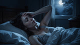 Woman cooling down from night sweats in a dark bedroom under cool moonlight