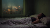 Person lying awake on a muggy humid night with condensation on the bedroom window